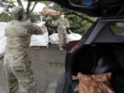 Members of the Washington National Guard toss a bag of potatoes as they load a waiting car, Thursday, May 14, 2020, during the free distribution of 200,000 pounds of potatoes provided by the Washington State Potato Commission in Tacoma, Wash. Most of the potatoes were donated by farmers across the state who have not been able to sell to their regular restaurant customers due to the coronavirus pandemic. (AP Photo/Ted S.