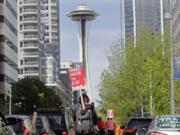 A protester carries a sign that reads &quot;Unionize Amazon Tax Bezos,&quot; while riding a bike during a car-based protest Friday, May 1, 2020, at the Amazon Spheres in downtown Seattle. May Day in Seattle traditionally brings large protests and demonstrations from many groups and causes, and this year some people stayed in their cars or otherwise tried to practice social distancing due to the outbreak of the coronavirus. (AP Photo/Ted S.