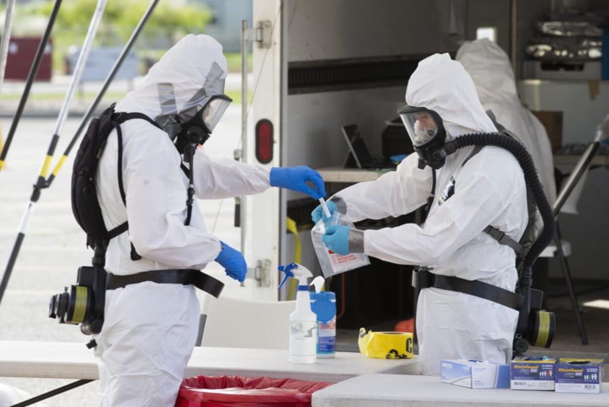 Army National Guard members bag a nasal swab at a drive-thru COVID-19 testing site Thursday at Highland High School in Cowiche.