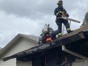 Vancouver Fire Department firefighters inspect the attic space of a garage that caught fire Monday.