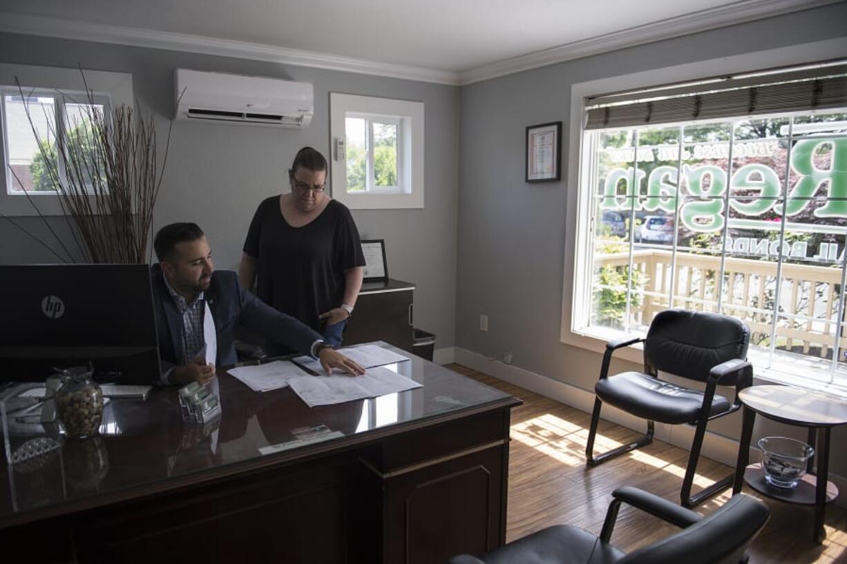 Owner David Regan talks with manager/operator Crystal Jeanty as they look over client contracts at Regan Bail Bonds in downtown Vancouver.