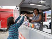 Natalie Oliver of Vancouver, left, picks up an order from Dorothy Golson at Golson&#039;s food cart, Southern Girl Delights. Golson said she opened the food cart in Hazel Dell a year ago, with a menu inspired by her upbringing in Alabama. &quot;I always followed my mom around in the kitchen,&quot; she said.