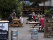 Backwoods Brewing Company server Crystal Badley, with mask, takes an order from customers seated in the outdoor dining area Thursday afternoon at the Carson establishment.