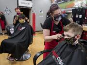 Manager Melissa New, second from right, lends a hand as Elliot Reichstein, 7, of Ridgefield gets a much-needed trim at SportClips on Monday afternoon in Hazel Dell after being in quarantine for COVID-19.