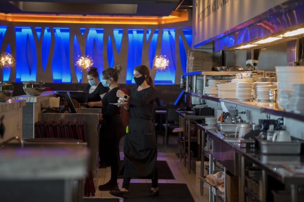 Twigs Bistro employee Bailey Gray, center, prepares to serve ice cream with a candle for a customer&#039;s birthday. Servers are wearing masks to reduce transmission of the novel coronavirus.