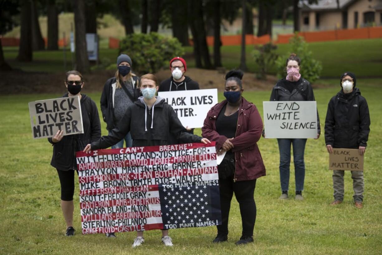 Demonstrators gather with signs at a Southwest Washington Communities United for Change rally at Vancouver Central Park on Monday afternoon.