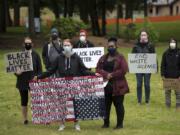 Demonstrators gather with signs at a Southwest Washington Communities United for Change rally at Vancouver Central Park on Monday afternoon.