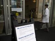 Dr. Greg Gramstad of Rebound Orthopedics & Neurosurgery walks past an informational sign for visitors to Legacy Salmon Creek Medical Center in Vancouver in June 2020.