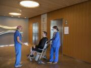 Dr. Nelson Saldua, from left, talks with his patient, Scott Poverud of Vancouver, as he is wheeled out of the hospital by registered nurse Katie Yochim-Smith after having surgery at Legacy Salmon Creek Medical Center in Vancouver. Saldua said it was tough for him to take a break from surgery during the pandemic because his patients needed care.