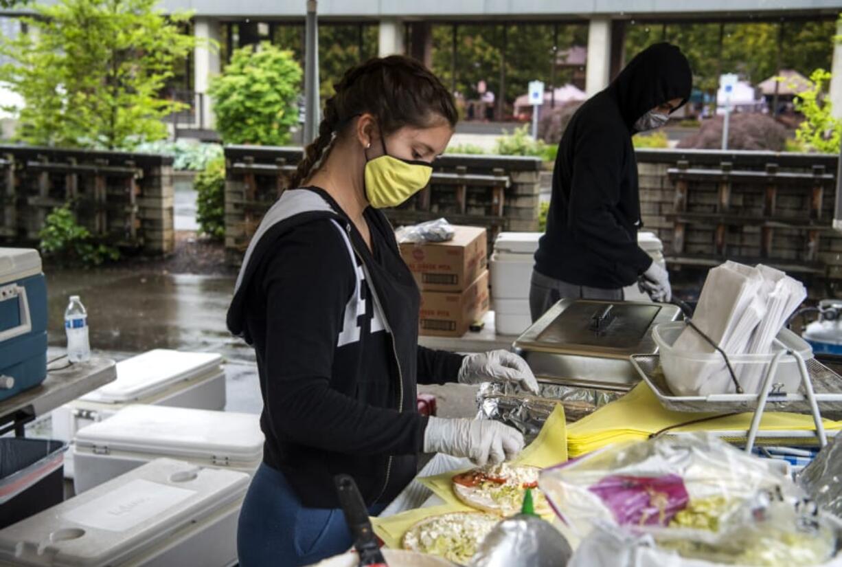 Kolby Wolfe, left, and Adolfo Santos whip up Gyros at the Greek Gyros booth at the Vancouver Farmers Market on Saturday. The market was initially limited to grocery vendors this year, but the lineup has gradually expanded to include hot food vendors.