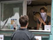 Funky Fresh Juice co-owner Rebekah Trigg, right, helps customers at the Vancouver Farmers Market in downtown Vancouver. As Clark County applies to enter Phase 3 of reopening, masks are required across the state.