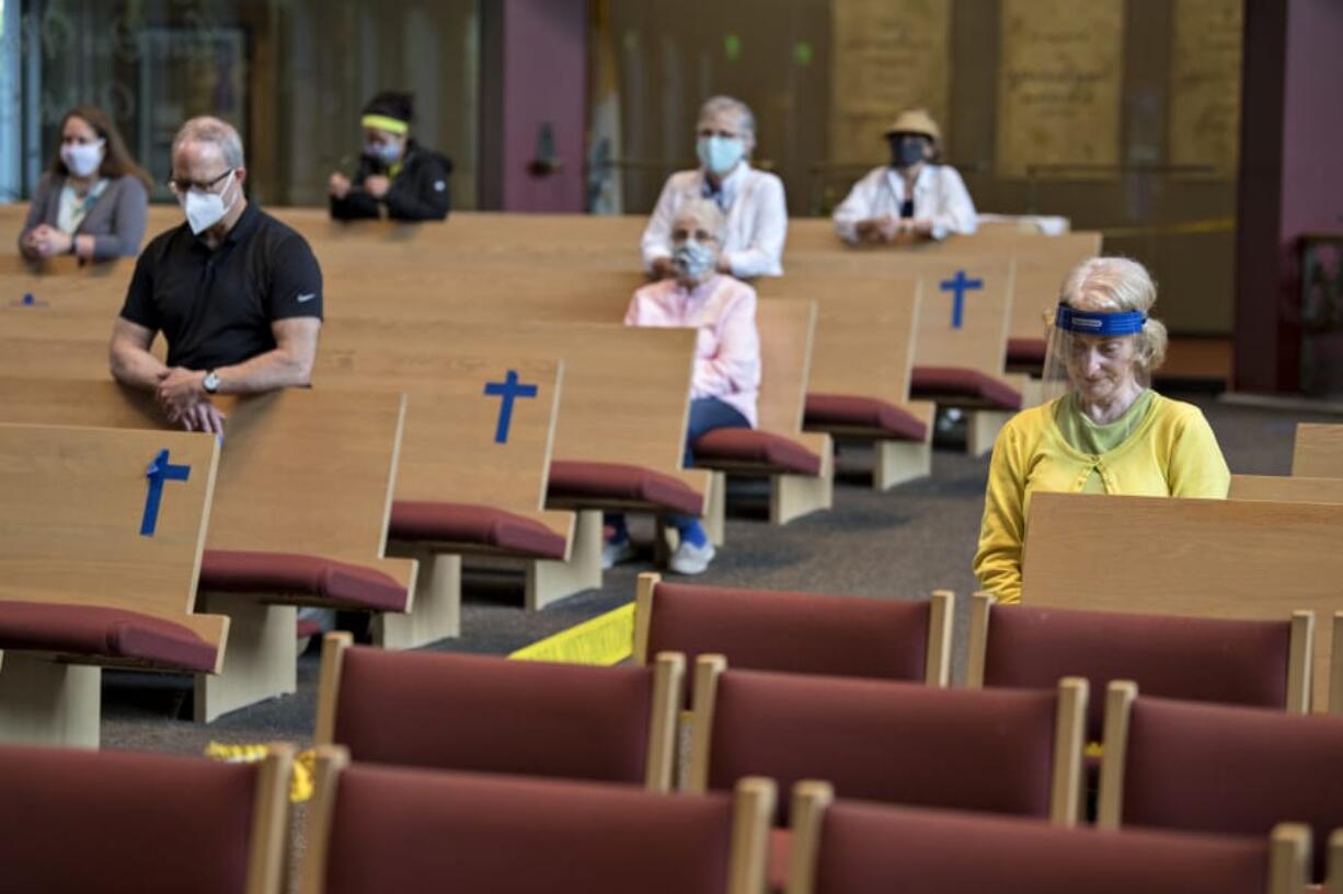 Connie Kessinger, right, bows her head in prayer before the Thursday morning service at St. Joseph Catholic Church. As churches slowly reopen, the traditional Catholic Mass has shifted to adapt to COVID-19.