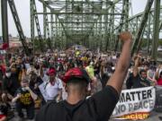 Hundreds of demonstrators take a knee for one minute to honor Black lives lost to police violence on the Interstate 5 bridge Friday afternoon, June 19, 2020.