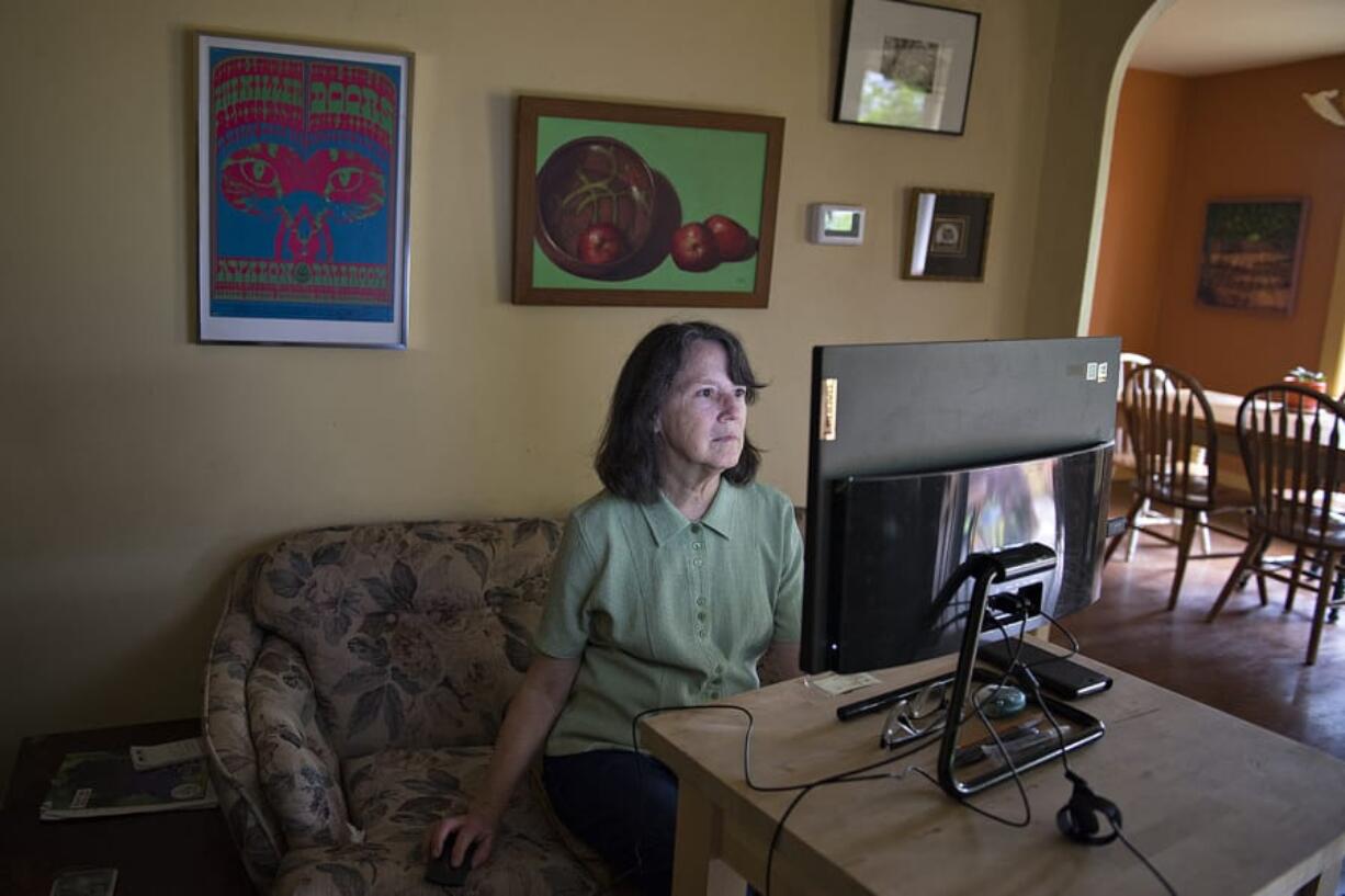 Sally Tomlinson, 67, art history professor at Clark College, is pictured at her home in Vancouver as a vintage poster from legendary band, The Doors, top left, is seen overhead. Tomlinson, who resides in Vancouver, has written essays on rock posters. &quot;I see it as my job to make people comfortable with art,&quot; she said.