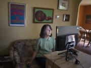 Sally Tomlinson, 67, art history professor at Clark College, is pictured at her home in Vancouver as a vintage poster from legendary band, The Doors, top left, is seen overhead. Tomlinson, who resides in Vancouver, has written essays on rock posters. &quot;I see it as my job to make people comfortable with art,&quot; she said.