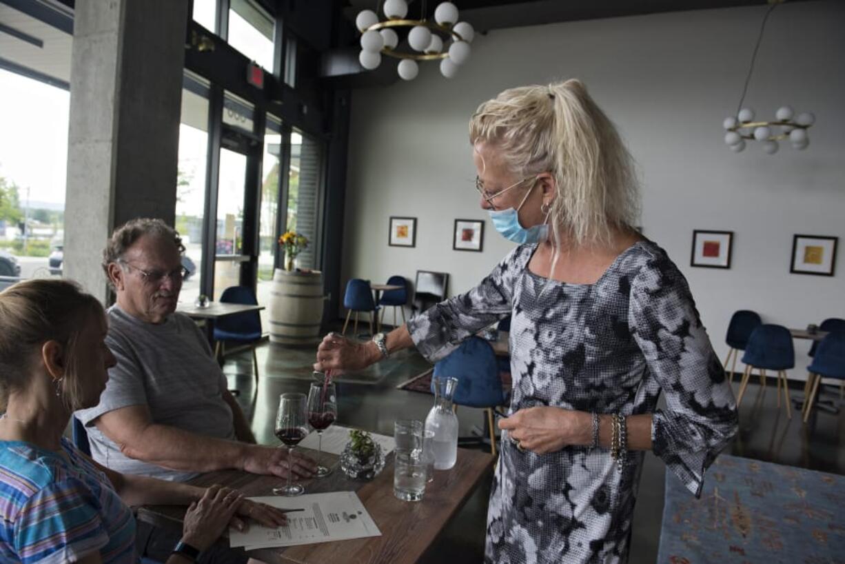 Trish Masters, from left, and George Gittelson of Vancouver try a taste from a bottle of Tuttorosso as associate Wynn Anderson pours a sample at Brian Carter Cellars on Wednesday. Wineries are open under Phase 2, and Brian Carter Cellars opened its doors for the first time on Wednesday.