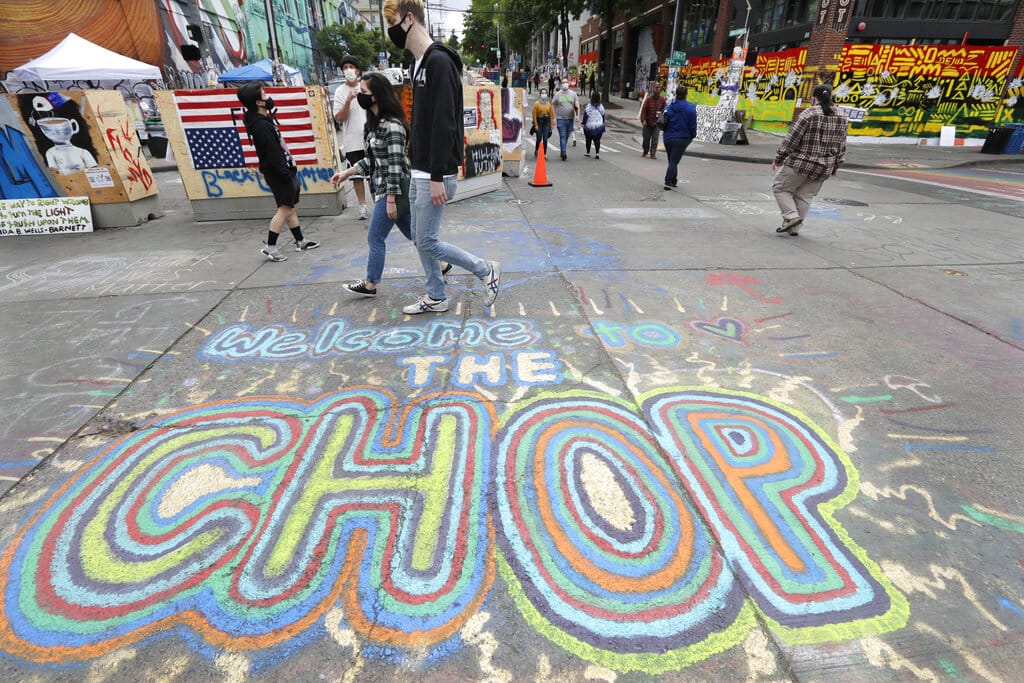 Pedestrians walk Sunday, June 21, 2020, in Seattle, where streets are blocked off in what has been named the Capitol Hill Occupied Protest (CHOP) zone. Police pulled back from several blocks of the city's Capitol Hill neighborhood near the Police Department's East Precinct building earlier in the month after clashes with people protesting the death of George Floyd.