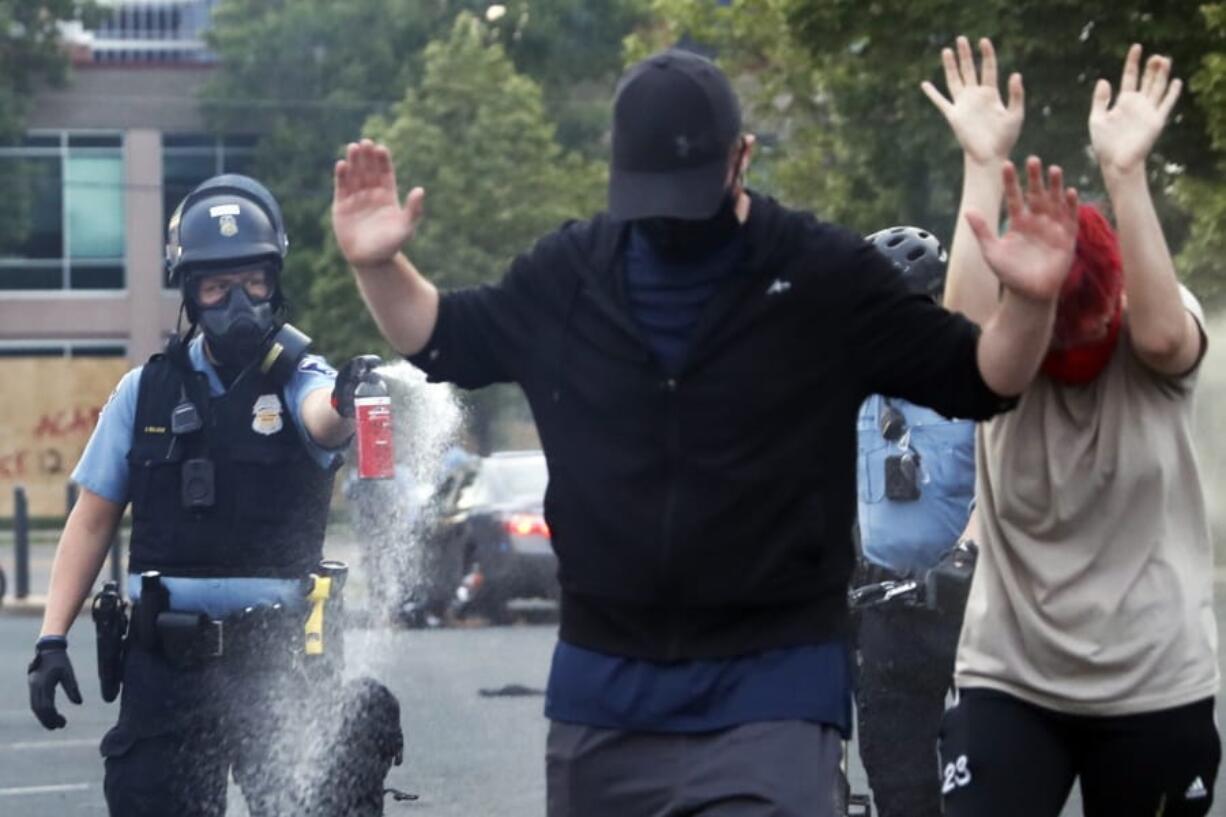 An officer points pepper spray toward people after curfew on Sunday in Minneapolis. Protests continued following the death of George Floyd, who died after being restrained by Minneapolis police officers on Memorial Day.