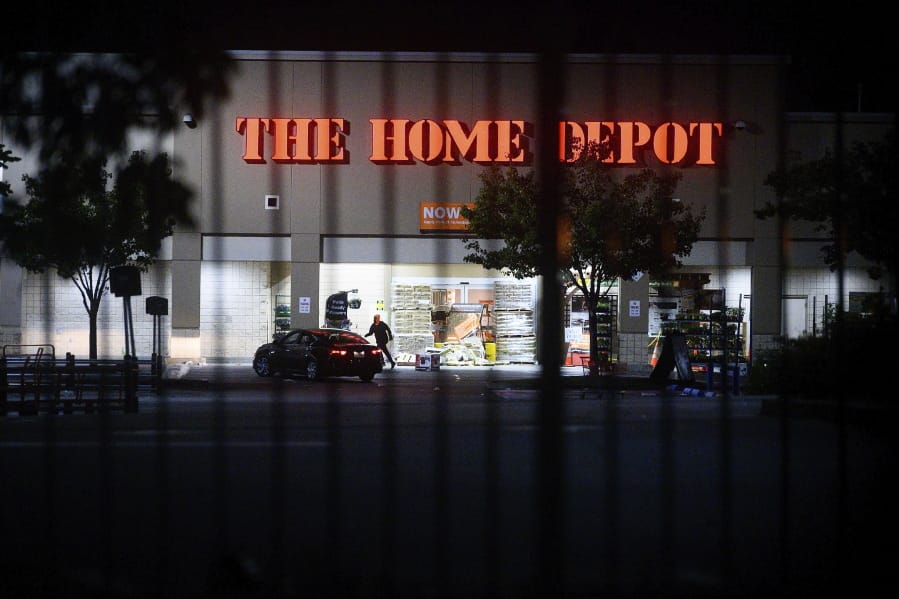 FILE - In this June 1, 2020, file photo, a man leaves a vandalized Home Depot store in Oakland, Calif. Police say many of the smash-and-grab thefts have been carried out by caravans of well-coordinated criminals that have coincided with or followed protests over the death of George Floyd, who was killed by a Minneapolis police officer who pressed his knee into Floyd&#039;s neck.