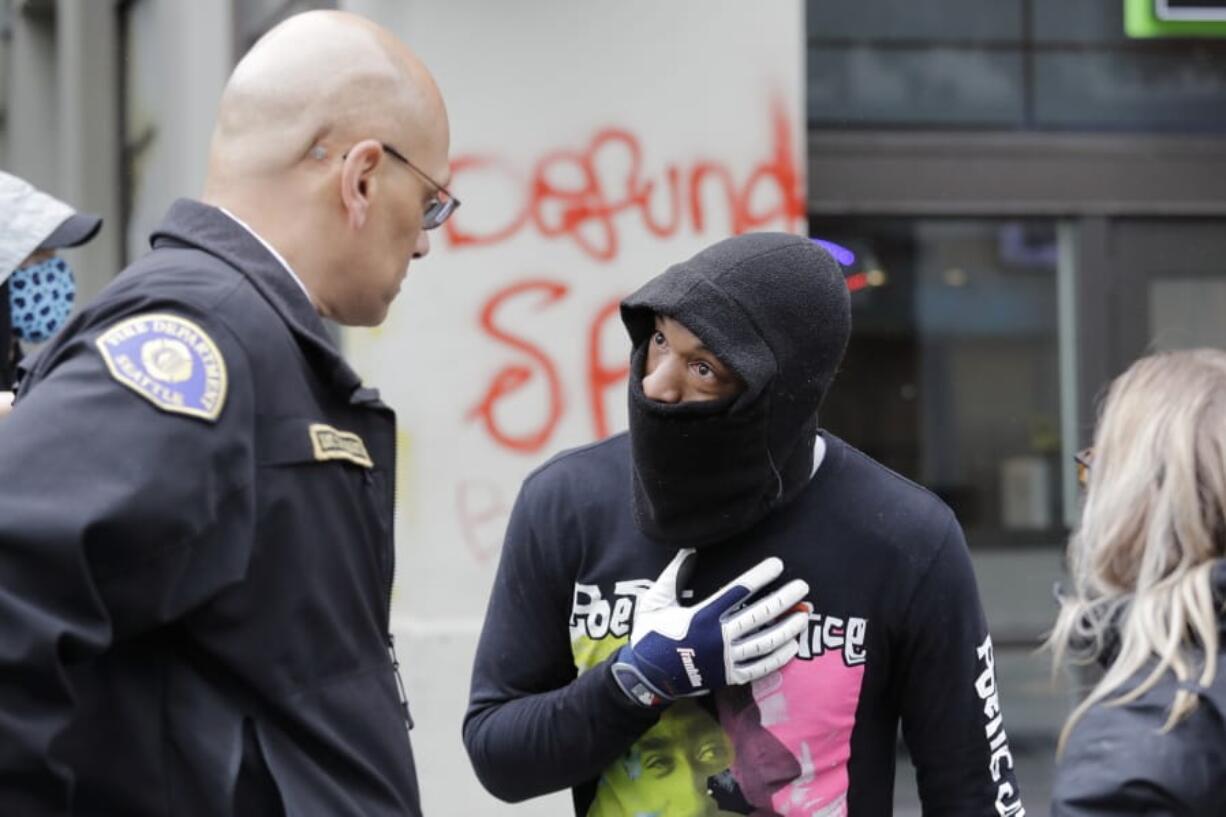 Demonstrator Keith Brown, right, talks with Seattle Fire Dept. Assistant Chief Willie Barrington as they plan to remove makeshift barricades protesters had put up in the streets next to a Seattle police precinct Tuesday, June 9, 2020, in Seattle, following protests over the death of George Floyd. Floyd, a black man died after being restrained by Minneapolis police officers on May 25.