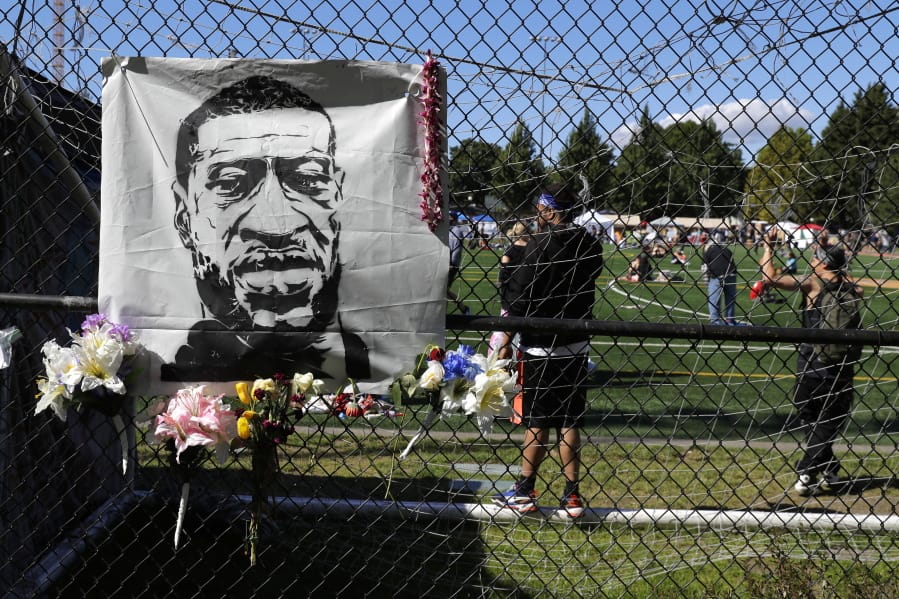 Flowers are placed next to an image of George Floyd on a fence surrounding Cal Anderson Park, Wednesday, June 17, 2020, inside what has been named the Capitol Hill Occupied Protest zone in Seattle. Police pulled back from several blocks of the city&#039;s Capitol Hill neighborhood near the Police Department&#039;s East Precinct building earlier in the month after clashes with people protesting the police killing of Floyd in Minneapolis. (AP Photo/Ted S.