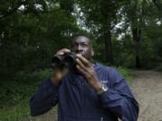 Keith Russell, program manager of urban conservation at Audubon Pennsylvania, lowers his binoculars while conducting a breeding bird census June 5 at Wissahickon Valley Park in Philadelphia.