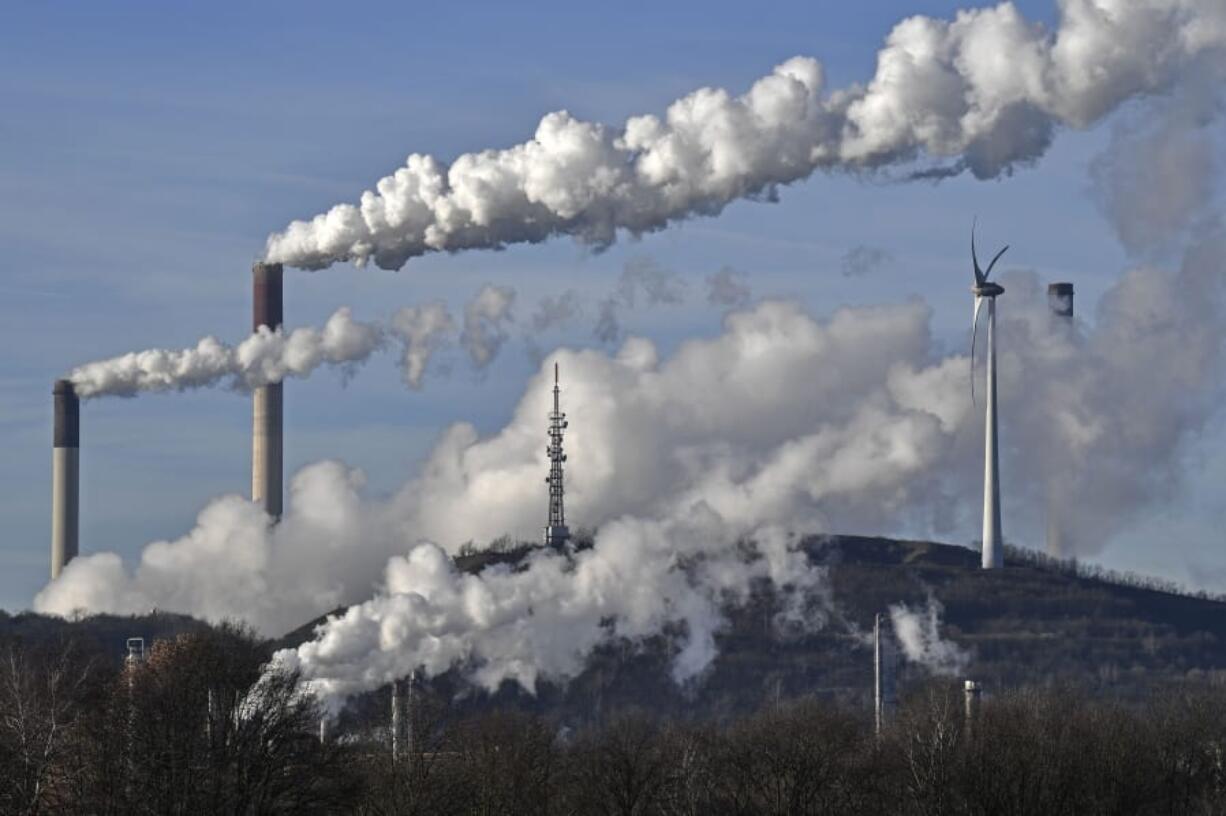 FILE - This Jan. 16, 2020 file photo shows a Uniper energy company coal-fired power plant and a BP refinery beside a wind generator in Gelsenkirchen, Germany. The world hit another new record high for heat-trapping carbon dioxide in the atmosphere, despite reduced emissions because of the coronavirus pandemic, scientists announced Thursday, June 4, 2020.