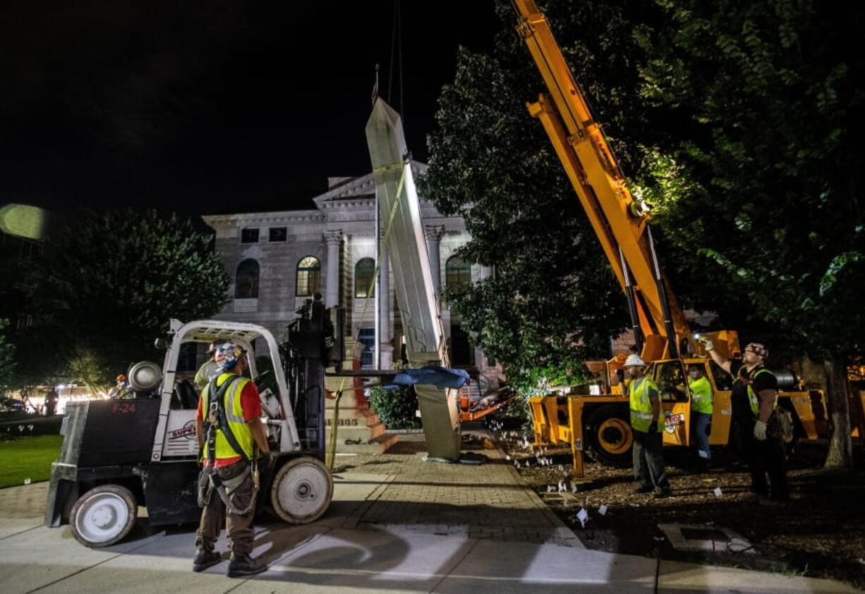 Workers remove a Confederate monument with a crane Thursday, June 18, 2020, in Decatur, Ga. The 30-foot obelisk in Decatur Square, erected by the United Daughters of the Confederacy in 1908, was ordered by a judge to be removed and placed into storage indefinitely.