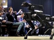 A Boston Dynamics SpotMini robot walks through a conference room during a robotics summit in Boston.