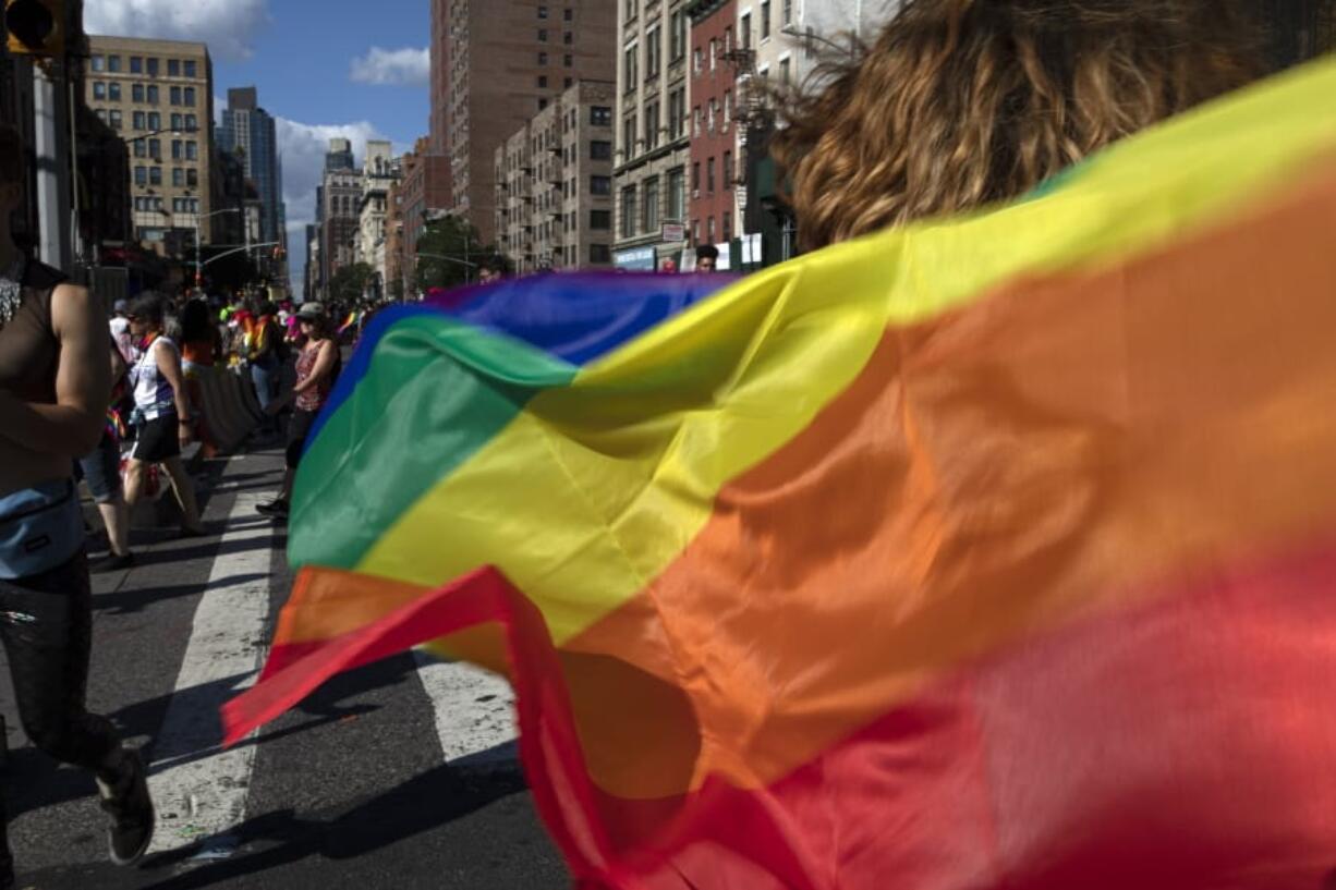 FILE - In this June 30, 2019, file photo parade-goers carrying rainbow flags walk down a street during the LBGTQ Pride march in New York, to celebrate five decades of LGBTQ pride, marking the 50th anniversary of the police raid that sparked the modern-day gay rights movement. Democrats flooded Twitter and email inboxes this week with praise for the watershed Supreme Court decision shielding gay, lesbian and transgender people from job discrimination.