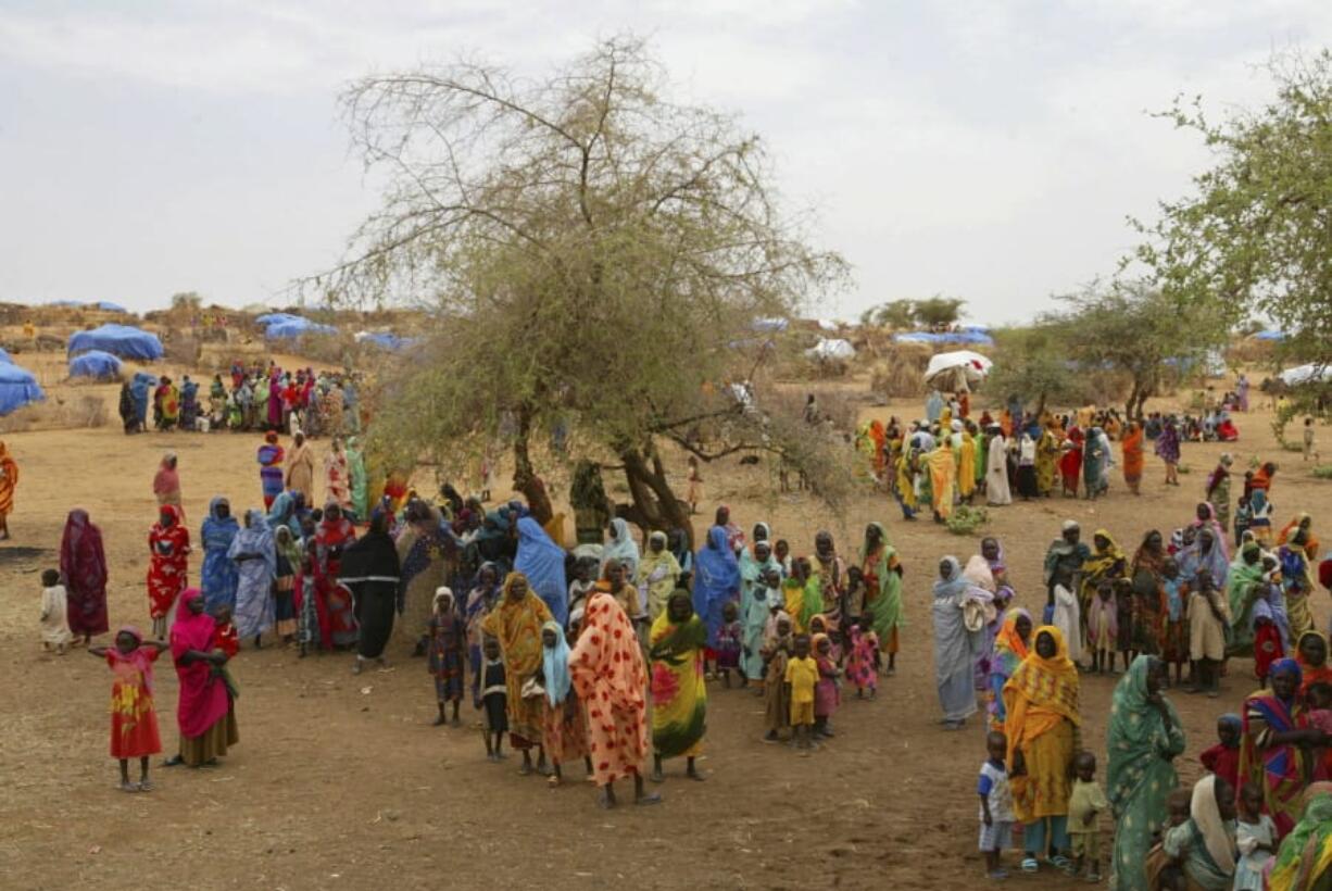 FILE - In this Thursday, July 1, 2004 file photo, Sudanese displaced women gather at the Zam Zam refugee camp just outside the town of El-Fashir in the Darfour region of Sudan, during a visit by U.N. Secretary General Kofi Annan. Sudanese militia leader Ali Kushayb, who is charged with 50 crimes against humanity and war crimes related to the conflict in Darfur, has been arrested more than 13 years after a warrant was issued for him, authorities said Tuesday, June 9, 2020.