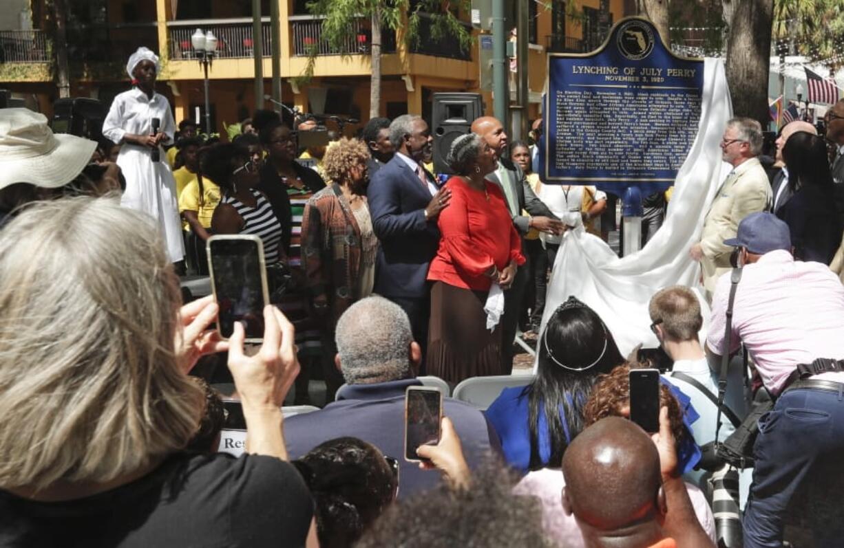 FILE- In this June 21, 2019 file photo, descendants of July Perry along with local elected officials and residents attend a ceremony unveiling a historical marker in Orlando, Fla. Perry was lynched by a white mob after helping a friend trying to vote. After Perry was lynched, the mob laid siege to the black section of Ocoee, Fla., killing dozens.