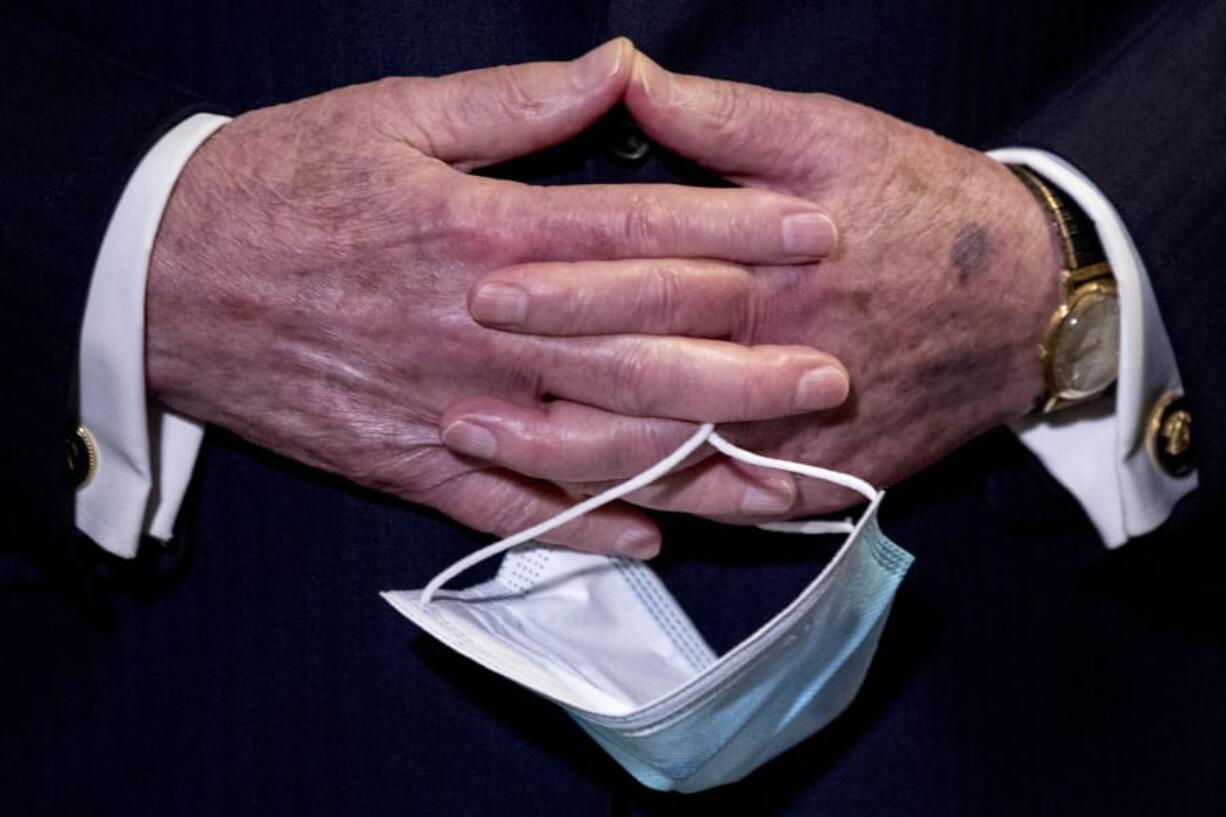 FILE - In this June 16, 2020, file photo Senate Majority Leader Mitch McConnell, R-Ky., holds a face mask in his hands during a news conference following a Senate policy luncheon on Capitol Hill in Washington. On Friday, June 26, Vice President Mike Pence said Americans should look to their state and local leadership for modeling their behavior during the coronavirus pandemic. The comments only days after President Donald Trump held two campaign events that drew hundreds of participants but few wearing masks.