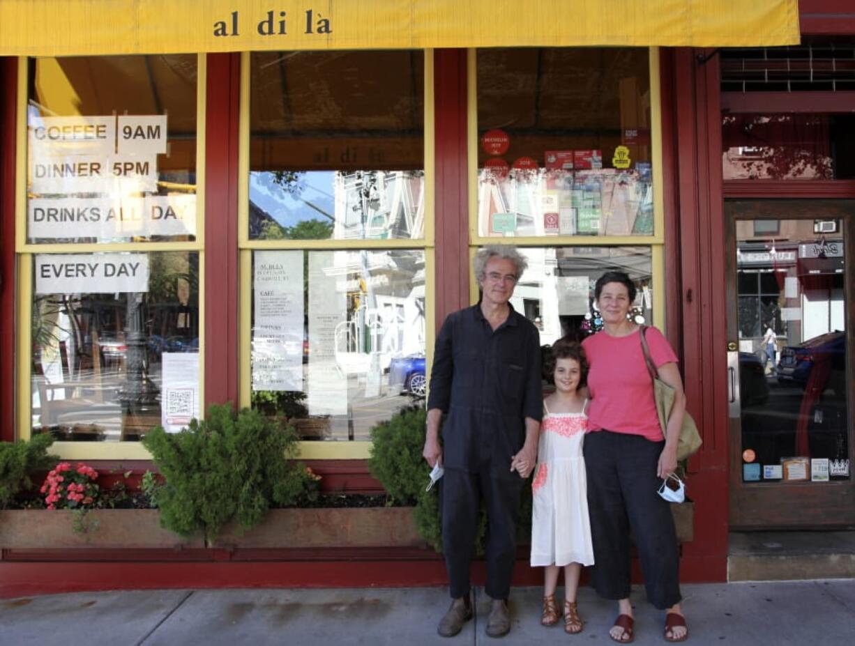 In this June 14, 2020 photo, Emiliano Coppa, left, and chef Anna Klinger pose with their daughter outside their trattoria, Al di La, in the Park Slope neighborhood in the Brooklyn borough of New York. The coronavirus has decimated the restaurant industry, leaving millions unemployed and shuttering spots for good. Many dine-in restaurants have turned to delivery or takeout, like Al di La.