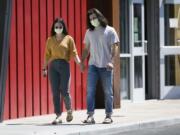 Hana Morris, left, and Forrest Golic wear masks as they walk hand in hand Monday, June 22, 2020, in Yakima.