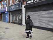 A woman walks past closes shops in Melton Road also known as the Golden Mile in Leicester, England, Tuesday June 30, 2020. The British government has reimposed lockdown restrictions in the English city of Leicester after a spike in coronavirus infections, including the closure of shops that don&#039;t sell essential goods and schools.