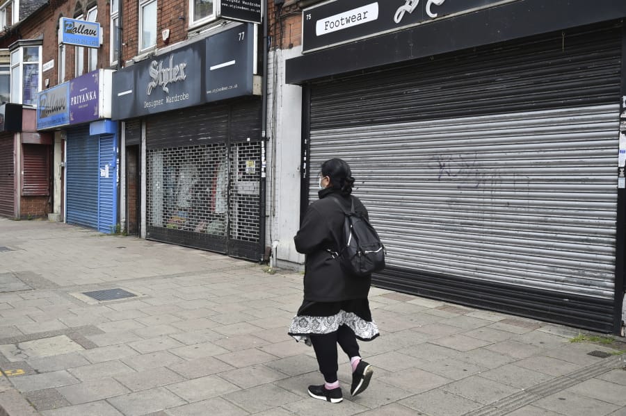 A woman walks past closes shops in Melton Road also known as the Golden Mile in Leicester, England, Tuesday June 30, 2020. The British government has reimposed lockdown restrictions in the English city of Leicester after a spike in coronavirus infections, including the closure of shops that don&#039;t sell essential goods and schools.