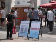 People wearing protective face masks to help curb the spread of the new coronavirus gather outside a hospital to seek information about getting the nucleic acid test in Beijing, Monday, June 15, 2020. Beijing has reinstated measures to control the spread of the coronavirus amid a growing outbreak.