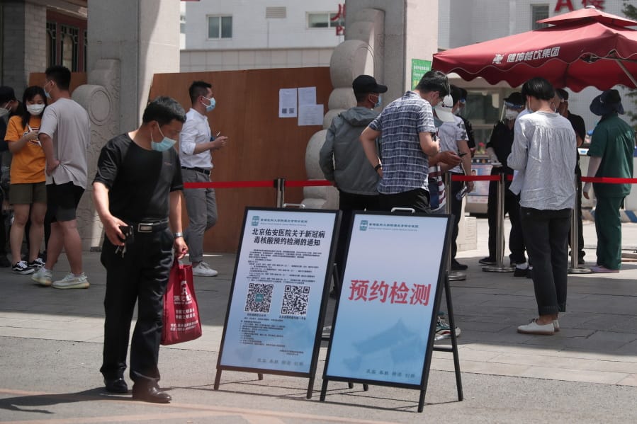 People wearing protective face masks to help curb the spread of the new coronavirus gather outside a hospital to seek information about getting the nucleic acid test in Beijing, Monday, June 15, 2020. Beijing has reinstated measures to control the spread of the coronavirus amid a growing outbreak.