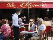 A bartender brings drinks to customers in a cafe of Saint Jean de Luz, southwestern France, Tuesday June 2, 2020. The French way of life resumes Tuesday with most virus-related restrictions easing as the country prepares for the summer holiday season amid the pandemic. Restaurants and cafes reopen Tuesday with a notable exception for the Paris region, the country&#039;s worst-affected by the virus, where many facilities will have to wait until June 22 to reopen.