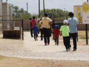 FILE - In this Aug. 23, 2019 file photo, immigrants seeking asylum hold hands as they leave a cafeteria at the ICE South Texas Family Residential Center in Dilley, Texas. The isolation of at least three families at the U.S. Immigration and Customs Enforcement&#039;s detention center in Dilley, has raised new fears of the coronavirus spreading through a facility that has long been accused of providing substandard medical care.