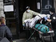 FILE- In this April 17, 2020, file photo, a patient is wheeled into Cobble Hill Health Center by emergency medical workers in the Brooklyn borough of New York. A grim blame game with partisan overtones is breaking out over COVID-19 deaths among nursing home residents, a tiny slice of the population that represents a shockingly high proportion of Americans who have perished in the pandemic.