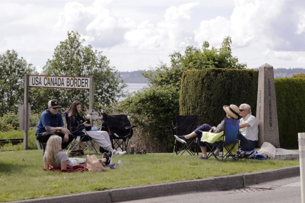 In this photo taken May 17, 2020, de Rham family members from the U.S. and Canada visit at the border between the countries in Peace Arch Park, in Blaine, Wash. With the border closed to nonessential travel amid the global pandemic, families and couples across the continent have found themselves cut off from loved ones on the other side. But the recent reopening of Peace Arch Park, which spans from Blaine into Surrey, British Columbia, at the far western end of the 3,987-mile contiguous border, has given at least a few separated parents, siblings, lovers and friends a rare chance for some better-than-Skype visits.