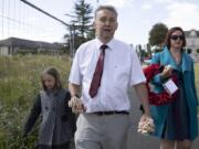 British expatriate Steven Oldrid, center, carries wooden crosses with names of WWII dead as he walks to the local war cemetery in Benouville, Normandy, France on Saturday, June 6, 2020. Due to coronavirus measures many relatives and veterans will not make this years 76th anniversary of D-Day. Oldrid will be bringing it to them virtually as he places wreaths and crosses for families and posts the moments on his facebook page.