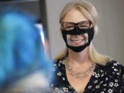 In this June 3, 2020, photo, Chris LaZich, of Fleet Science Center, wears a mask with a window as she talks with Delpha Hanson in San Diego.