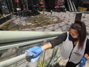 FILE - In this Thursday, June 11, 2020 file photo, Andrea Castaneda cleans the railings at Universal CityWalk near Universal City, Calif. On Friday, June 12, 2020, the Centers for Disease Control and Prevention posted guidelines to reduce the risk of COVID-19 coronavirus infection, along with a set of &quot;considerations&quot; for organizing and attending mass gatherings, as people emerge from stay-at-home lock downs and attempting some semblance of normal life. (AP Photo/Mark J.