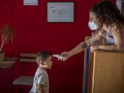 Hugo, 3, has his temperature taken by a teacher as he arrives at Cobi kindergarten in Barcelona, Spain, Friday, June 26, 2020. Spain&#039;s cabinet will extend the furlough schemes adopted during the coronavirus lockdown that brought the economy to a standstill until the end of September.