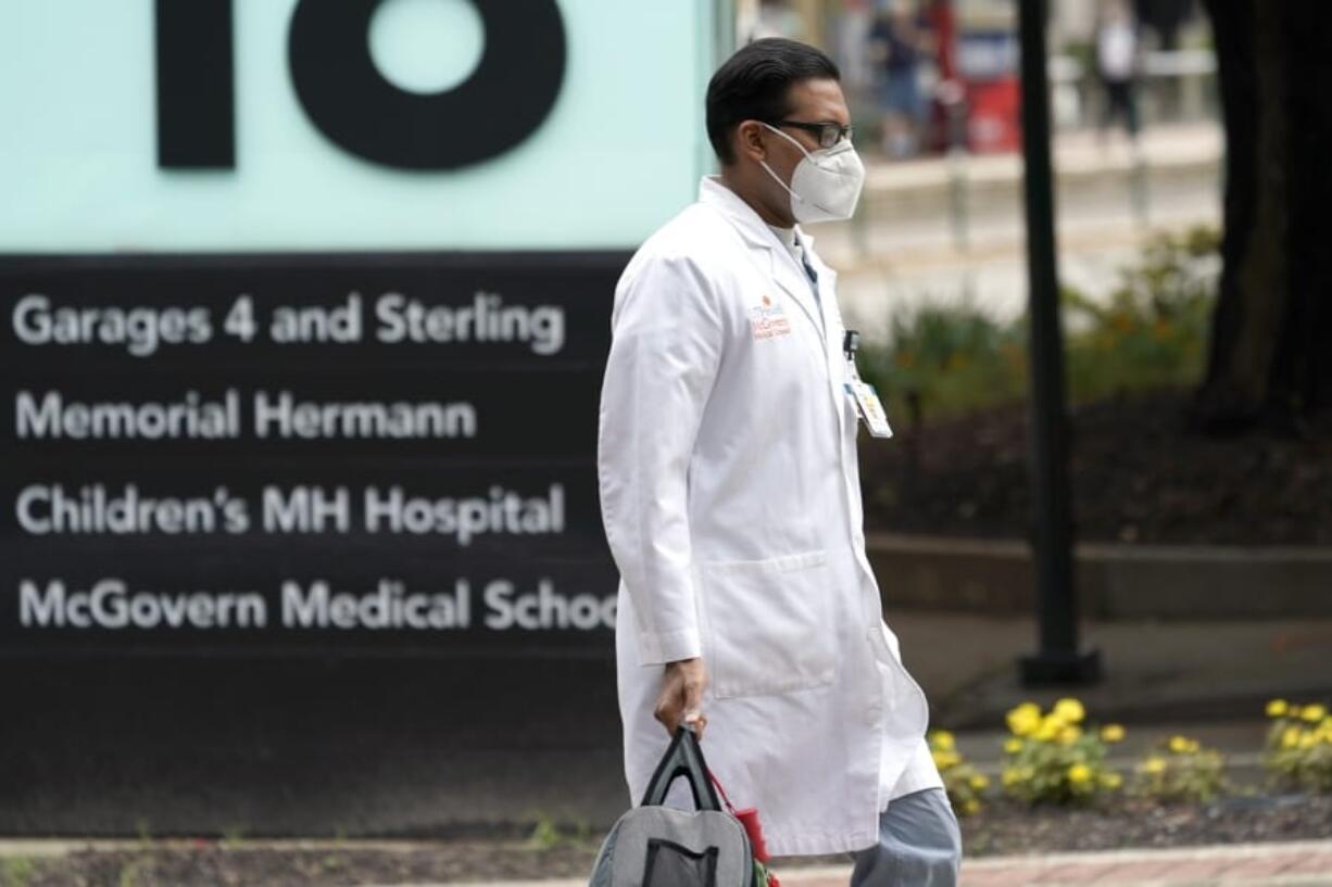 A healthcare professional walks through the Texas Medical Center Thursday, June 25, 2020, in Houston. The leaders of several Houston hospitals said they were opening new beds to accommodate an expected influx of patients with COVID-19, as coronavirus cases surge in the city and across the South. (AP Photo/David J.