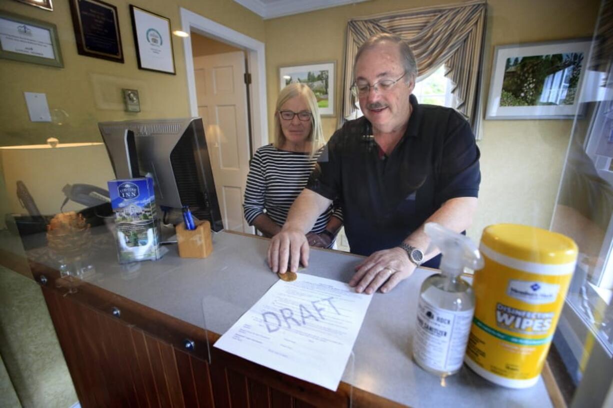 In this Wednesday, June 10, 2020, photo, Cod Cove Inn owners Ted and Jill Hugger show a draft of a compliance form that inn owners may be required to have out-of-state guests sign before being allowed to check in at their inn in Edgecomb, Maine. The form is part of the &quot;Keep Maine Healthy&quot; plan the state is proposing to help prevent the spread of the coronavirus. Residents of New Hampshire and Vermont would be exempt. (AP Photo/Robert F.