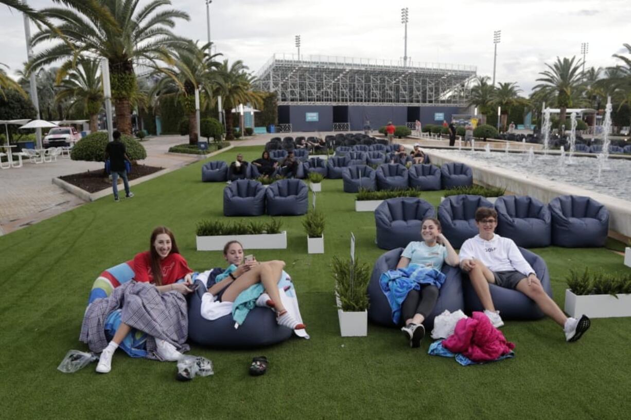 FILE - In this Thursday, June 18, 2020 file photo, people sit outdoors to watch a movie as part of a program offered by the Miami Dolphins at Hard Rock Stadium during the coronavirus pandemic in Miami Gardens, Fla. Elected officials such as Florida&#039;s governor have argued against reimposing restrictions, saying many of the newly infected are young and otherwise healthy. But younger people, too, face the possibility of severe infection and death. And authorities worry that older, more vulnerable people could be next.